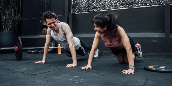 Man and woman doing pushups while smiling during a workout inside a Mexico City gym.